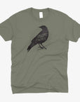 A heather olive green short-sleeve t-shirt with a distressed black graphic of a raven and the text 'DAUZAT ST. MARIE"